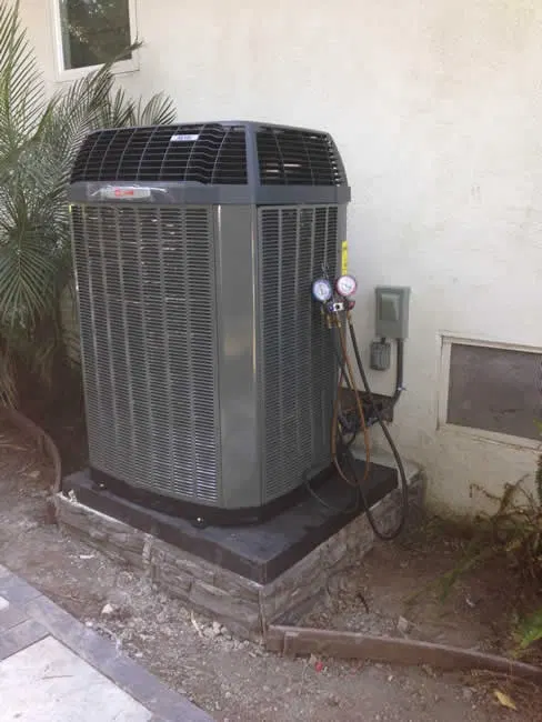 New outdoor AC unit installed next to a stucco wall